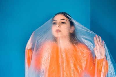 Portrait of woman standing against blue background