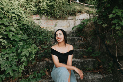 Portrait of young woman standing against plants