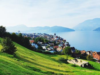 Scenic view of field by houses against sky