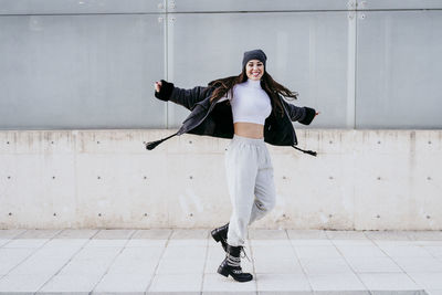 Full length portrait of woman standing against wall