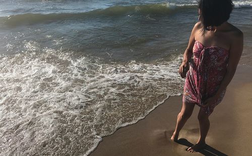 Rear view of woman standing on beach