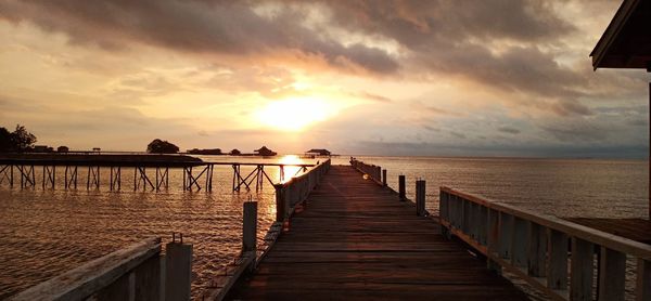 Pier over sea against sky during sunset