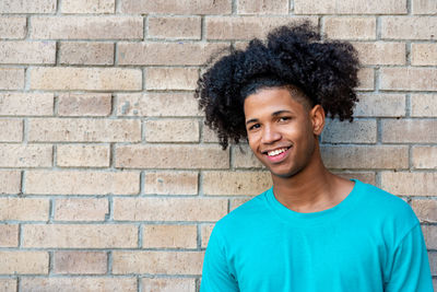 Portrait of a smiling young man against brick wall