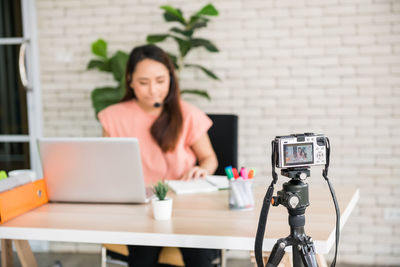 Young woman using laptop while sitting on table