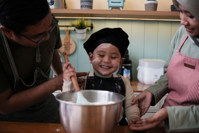 The little family was mixing dough cake in the kitchen.