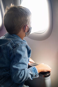 Rear view of boy sitting in airplane