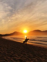 Silhouette man on beach against sky during sunset