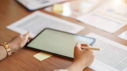 Midsection of woman using mobile phone on table