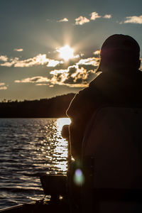 Rear view of silhouette man by sea against sky