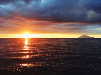 Scenic view of sea against dramatic sky during sunset