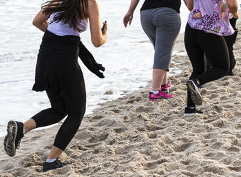 Low section of women running on beach