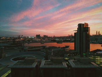 Illuminated cityscape against sky at sunset