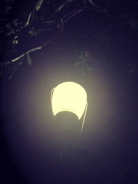 Low angle view of illuminated light bulb against dark sky