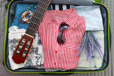 Close-up of guitar and clothes on luggage