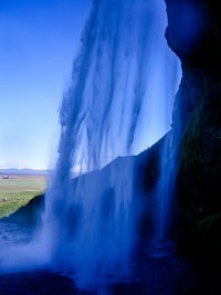 View of waterfall against blue sky