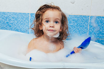 Cute shirtless girl sitting in bathtub at home