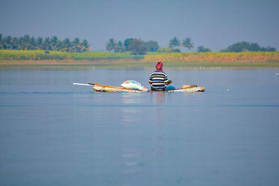 Rear view of man sitting on boat in lake