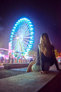 Illuminated ferris wheel against sky in city at night