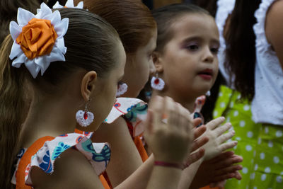 Side view of girls wearing dresses while clapping outdoors