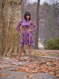 Full length of a smiling young woman standing in autumn