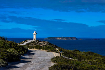 Lighthouse amidst sea and buildings against sky