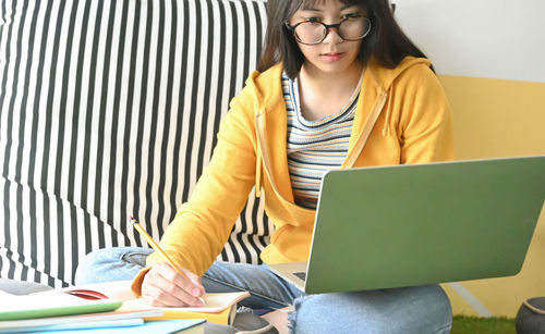 Young woman using mobile phone while sitting on table