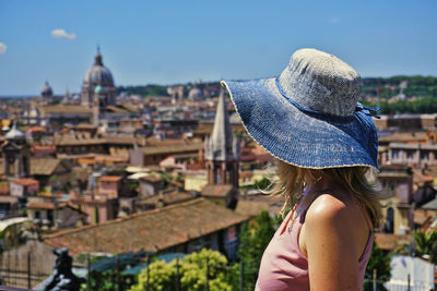 Rear view of woman looking at cityscape against sky