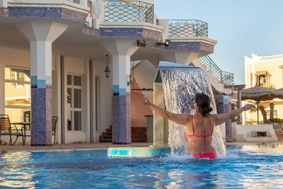 Woman enjoying under jet of hydromassage water with gentle splashes at spa resort. waterfall 