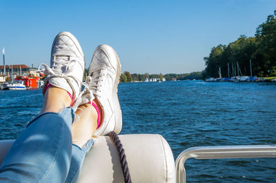 Low section of woman in boat on sea against sky