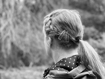 Black and white monochrome rear view of woman wearing hair clips walking in woodlands