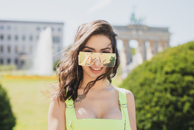 Portrait of fashionable young woman wearing sunglasses in city during sunny day