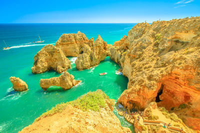 Panoramic view of rocks on beach against blue sky