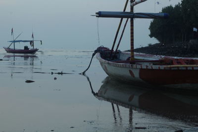 Sailboats moored on sea against sky