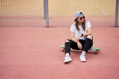 Female skateboarder sitting on board outdoors