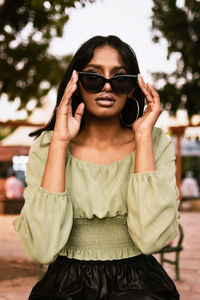 Portrait of young woman wearing sunglasses standing outdoors