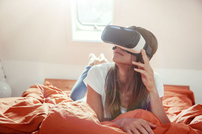 Young woman using mobile phone while sitting on bed at home