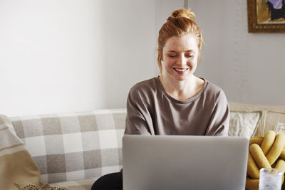 Smiling woman using laptop at home