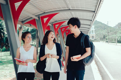 Happy friends talking while walking at college campus