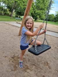 Portrait of smiling young girl jumping on swing 