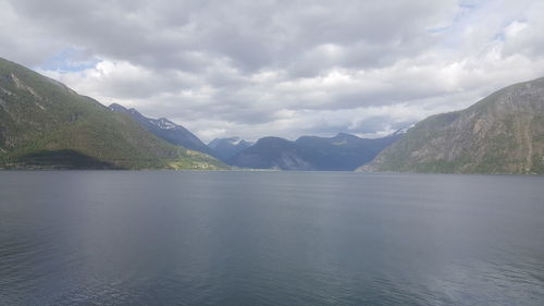 Scenic view of lake and mountains against cloudy sky