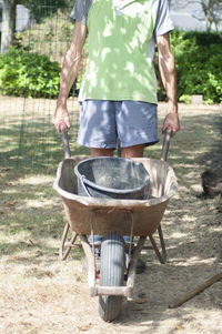 Gardener man in dirty work clothes, rolls a rusty cart with a bucket,spring work
