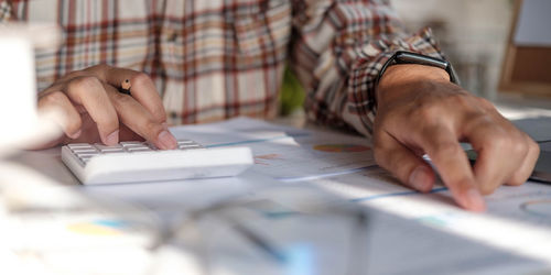 Close-up of hand holding paper with text on table