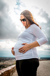 Midsection of young woman standing against sky