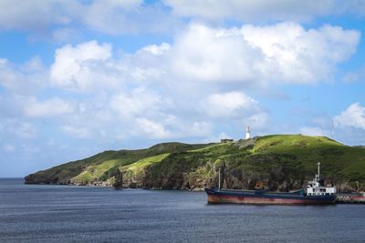 Boats sailing in sea against cloudy sky