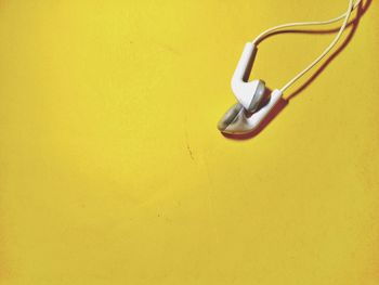 Close-up of earphones on yellow table