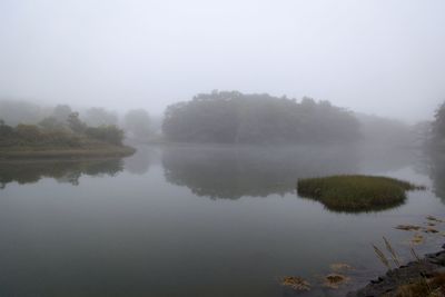 Scenic view of lake against sky during foggy weather