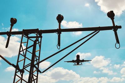 Low angle view of airplane flying over stoplight against sky