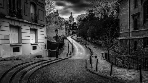 Empty road amidst buildings in city
