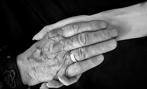 Close-up of woman holding hands against black background