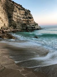 Rock formation on beach against sky